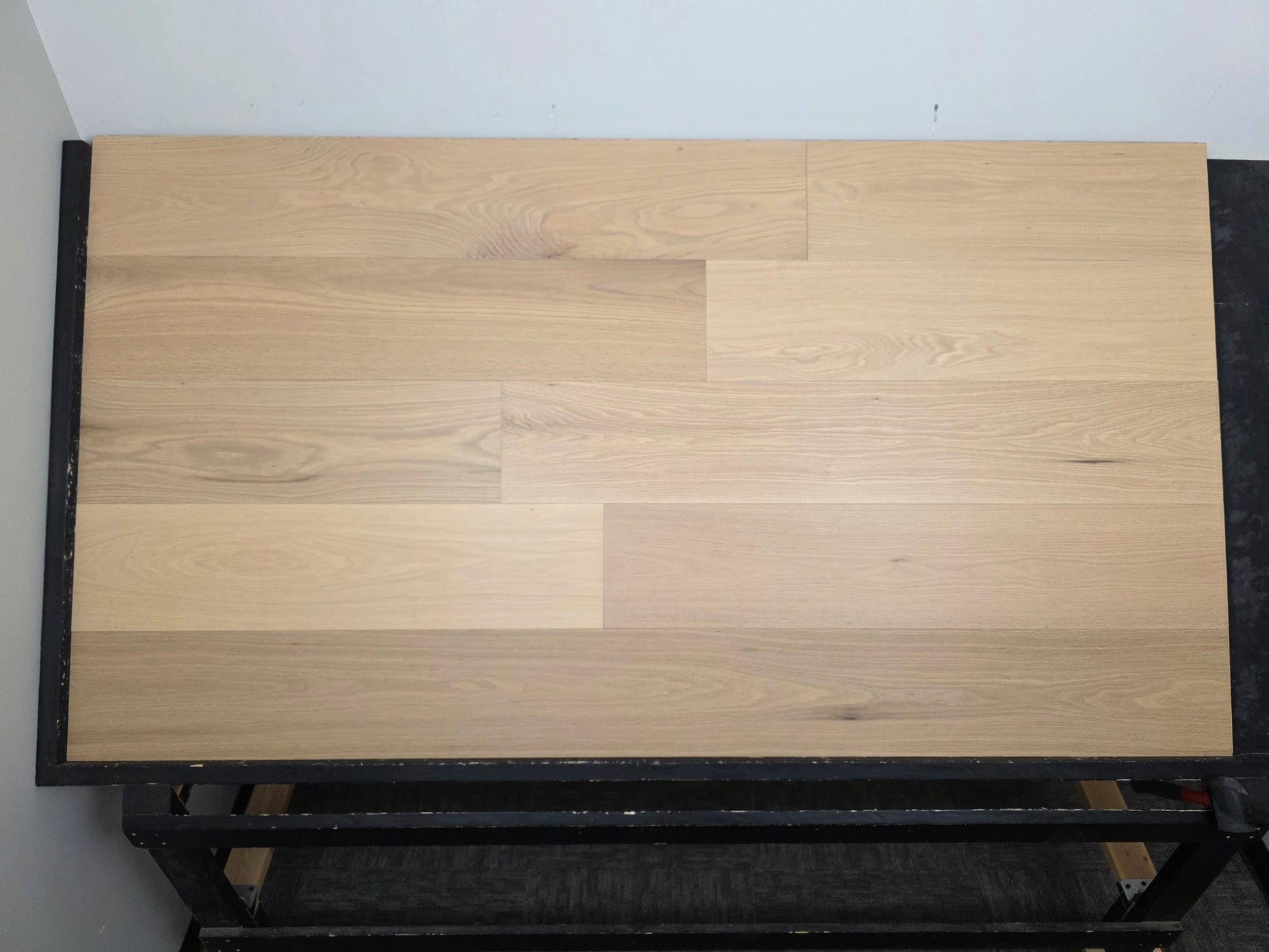 9 1/2" x 5/8" Engineered White Oak Sparrow Hardwood Flooring shown head on. Placed on a black shooting rack.