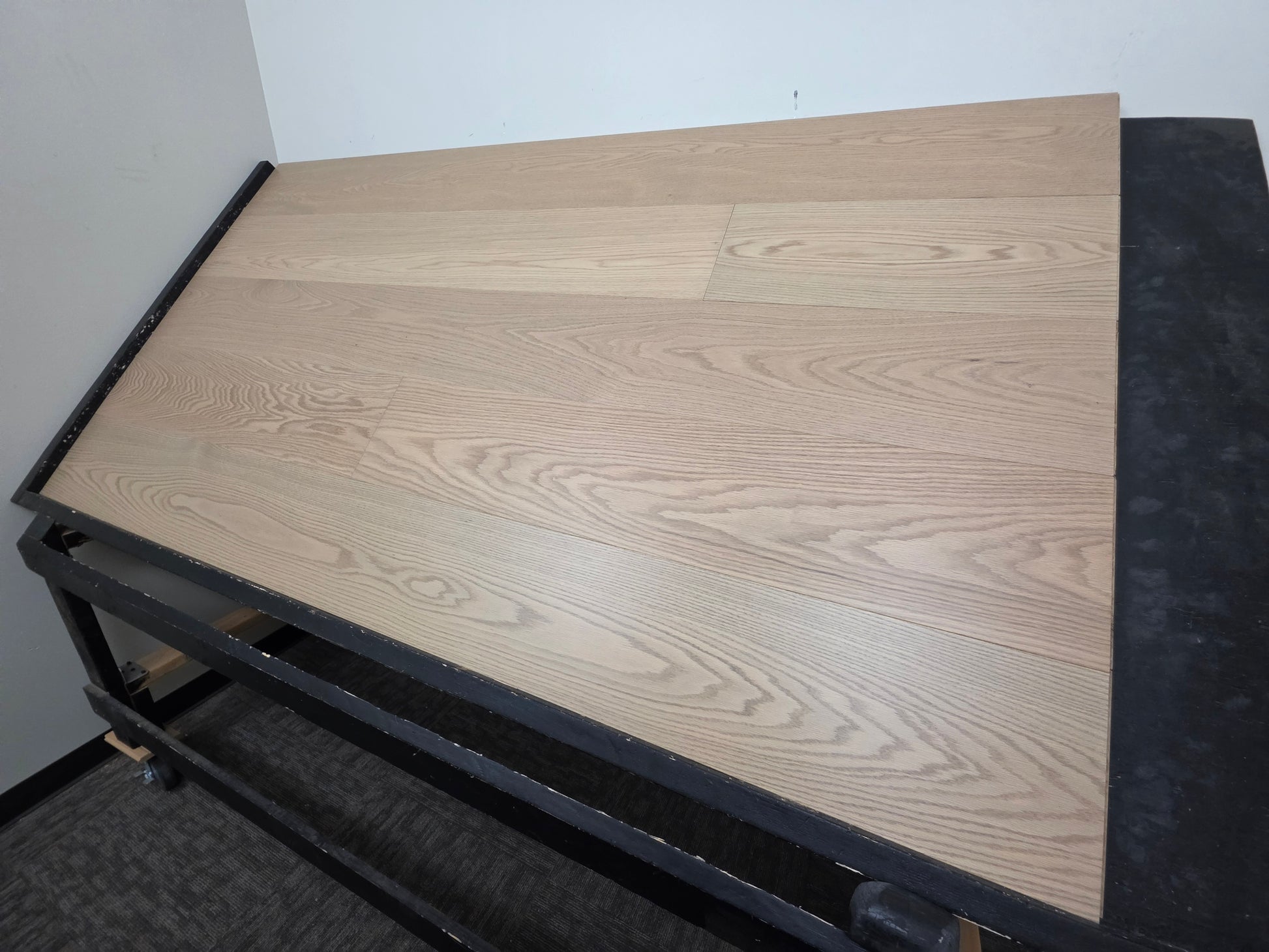 9 1/2" x 5/8" Engineered White Oak Swan Hardwood Flooring. Shown on a black shooting rack. Shown from the right side. 
