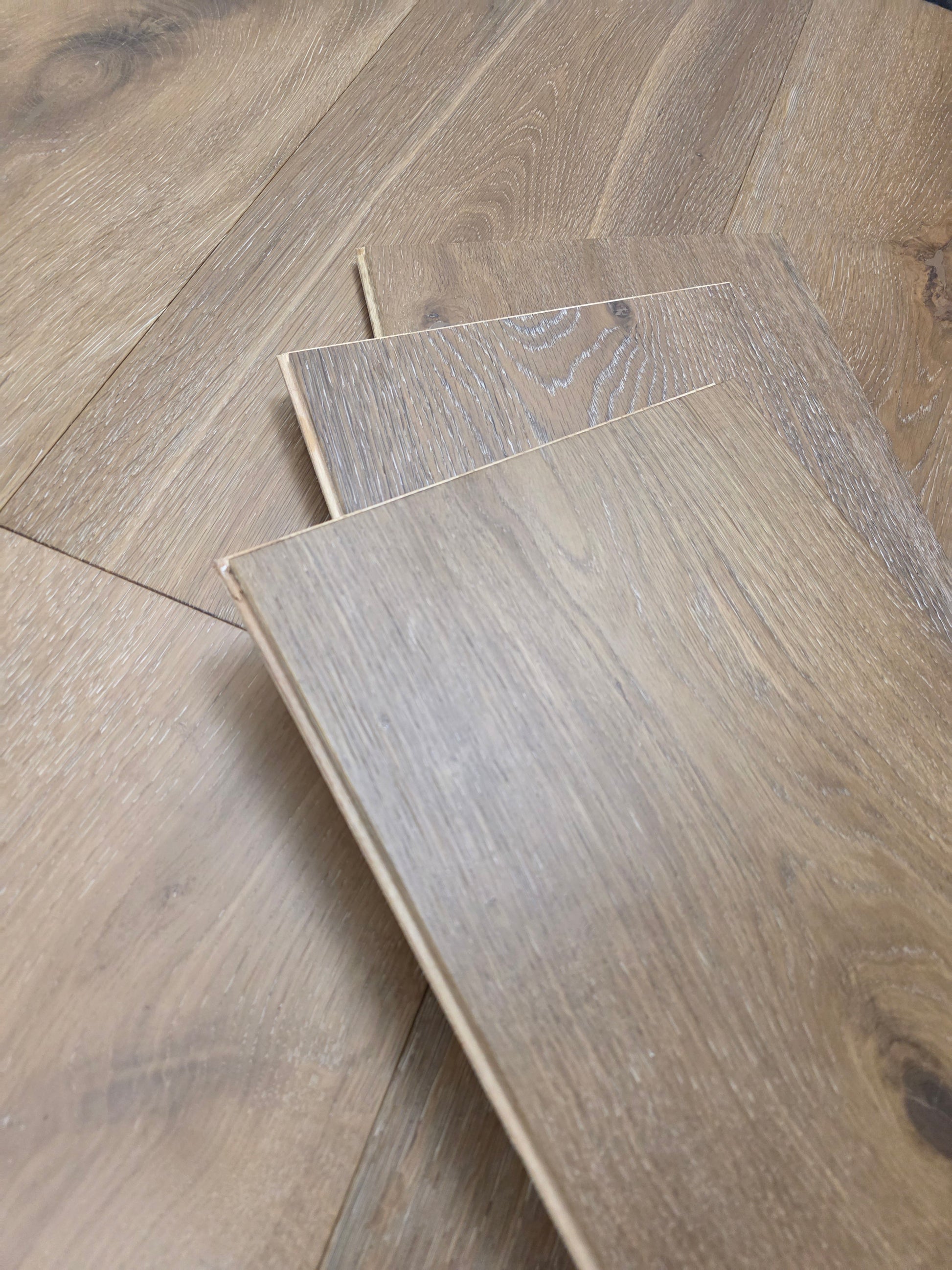 9 1/2" x 9/16" Engineered White Oak Atlas Hardwood Flooring shown stacked on top of the floor. stack is three planks high. 