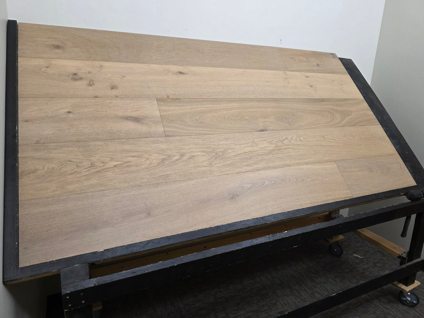 9 1/2" x 9/16" Engineered White Oak Elysian Hardwood Flooring. Shown on a black shooting table. Wide left angle shot. 