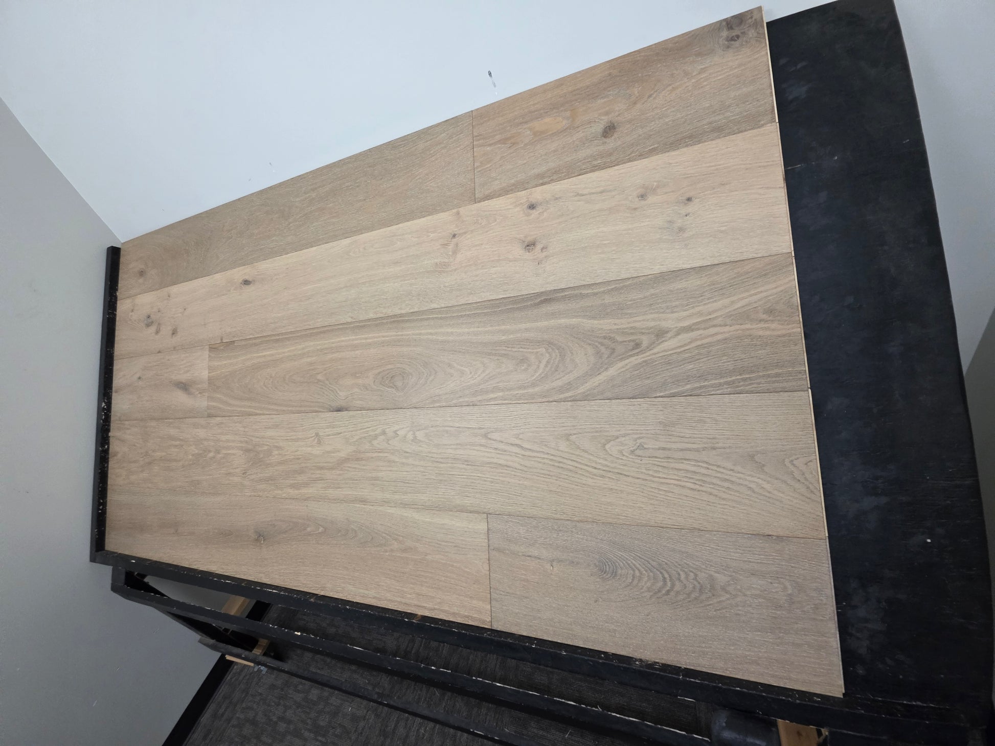 9 1/2" x 9/16" Engineered White Oak Elysian Hardwood Flooring. Shown on a black shooting table. Shot at a steep right angle.