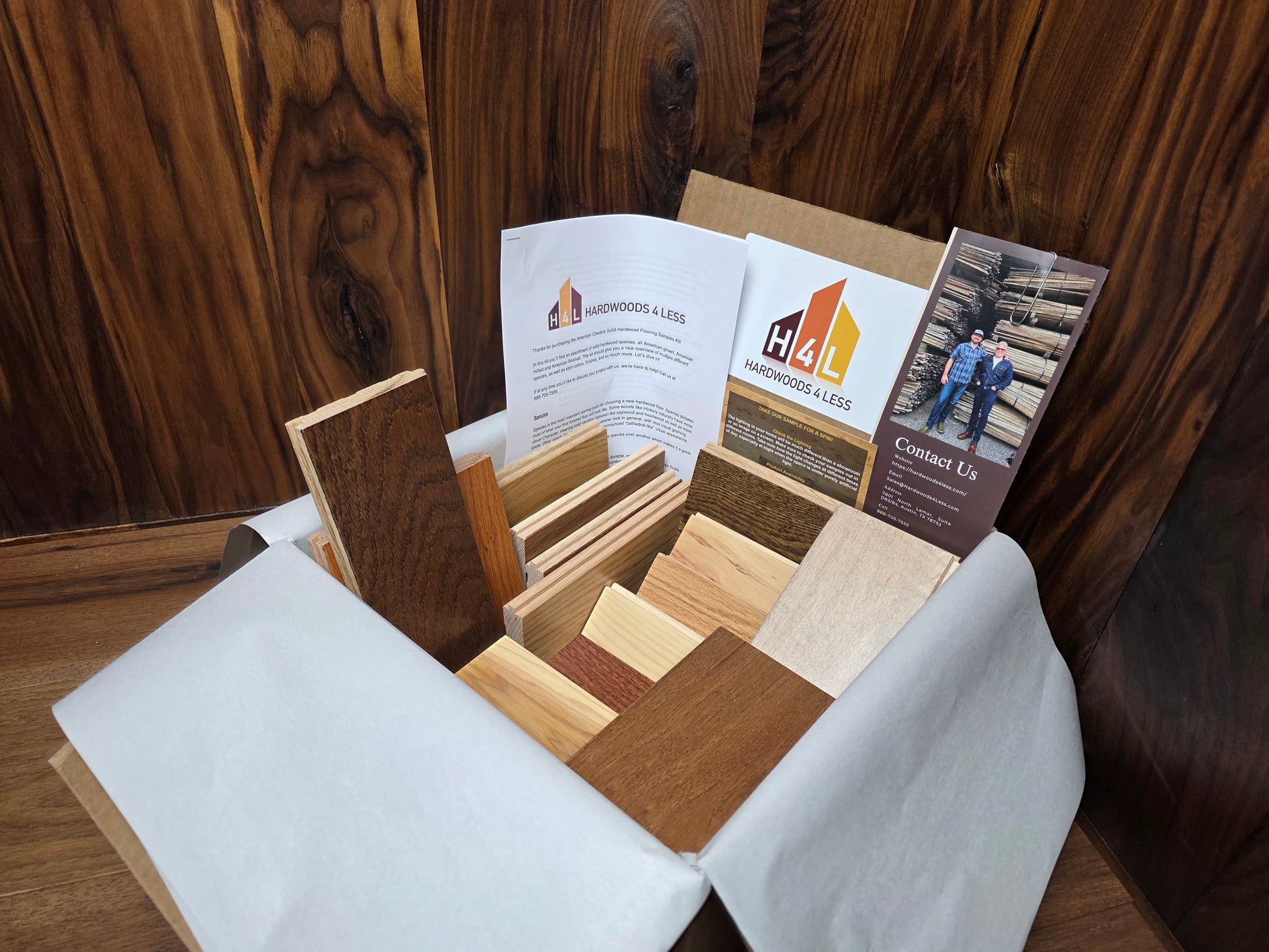 Hardwood Flooring sample box with wood swatches and brochures on a wooden surface