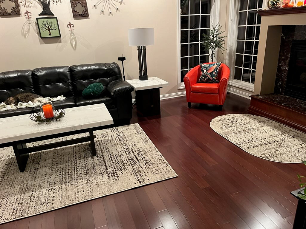 4" x 3/4" Solid Brazilian Oak Castanho Hardwood Flooring. Installed in a living room. Pictured from the center of the room. You see the floor under an area rug.