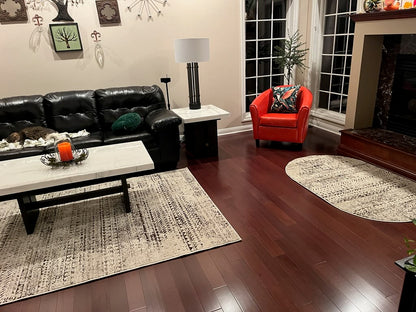 4" x 3/4" Solid Brazilian Oak Castanho Hardwood Flooring. Installed in a living room. Pictured from the center of the room. You see the floor under an area rug.