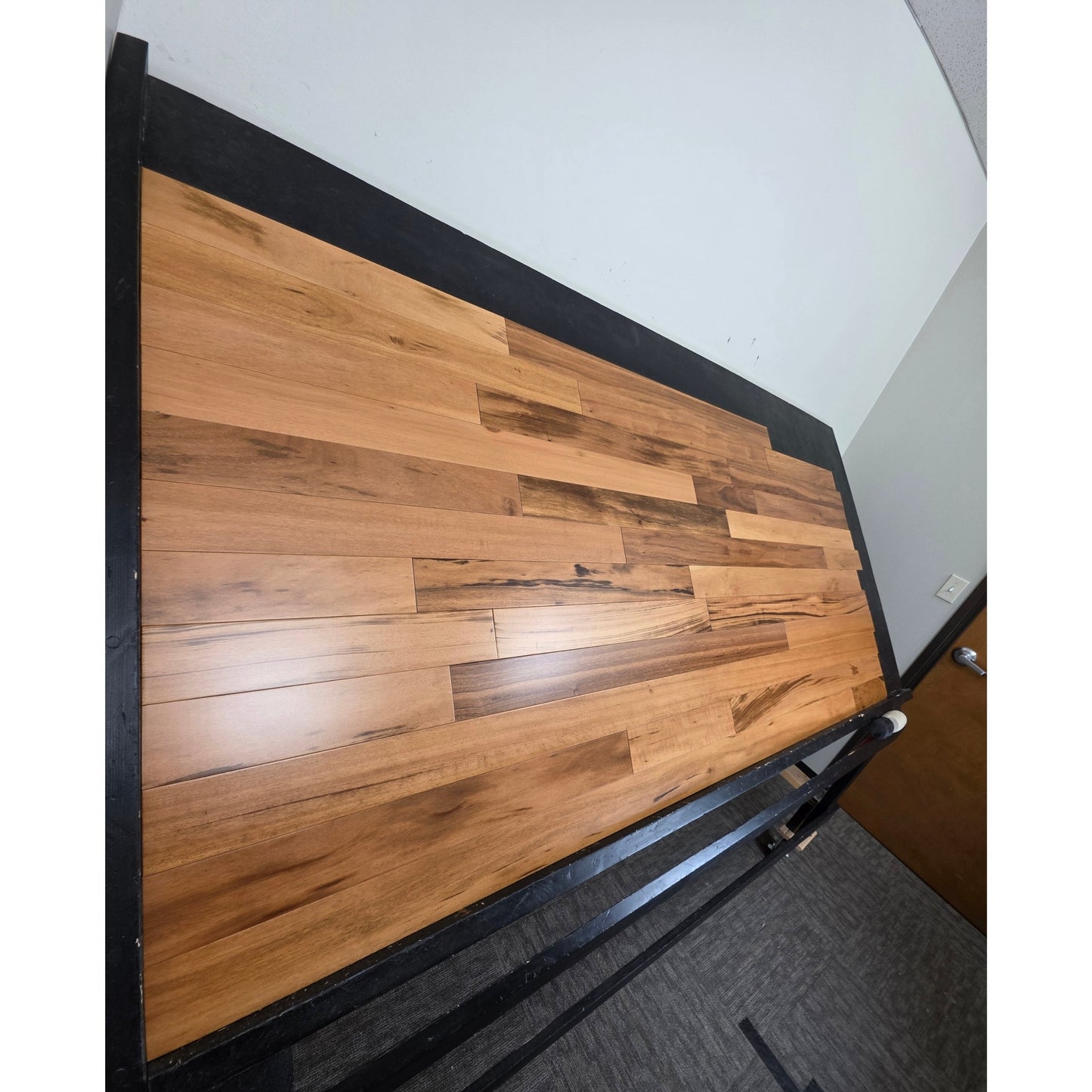 3 1/4" x 3/4" Solid Prefinished Tigerwood Hardwood Flooring. Shot from steep left. Shown on a black shooting table. 