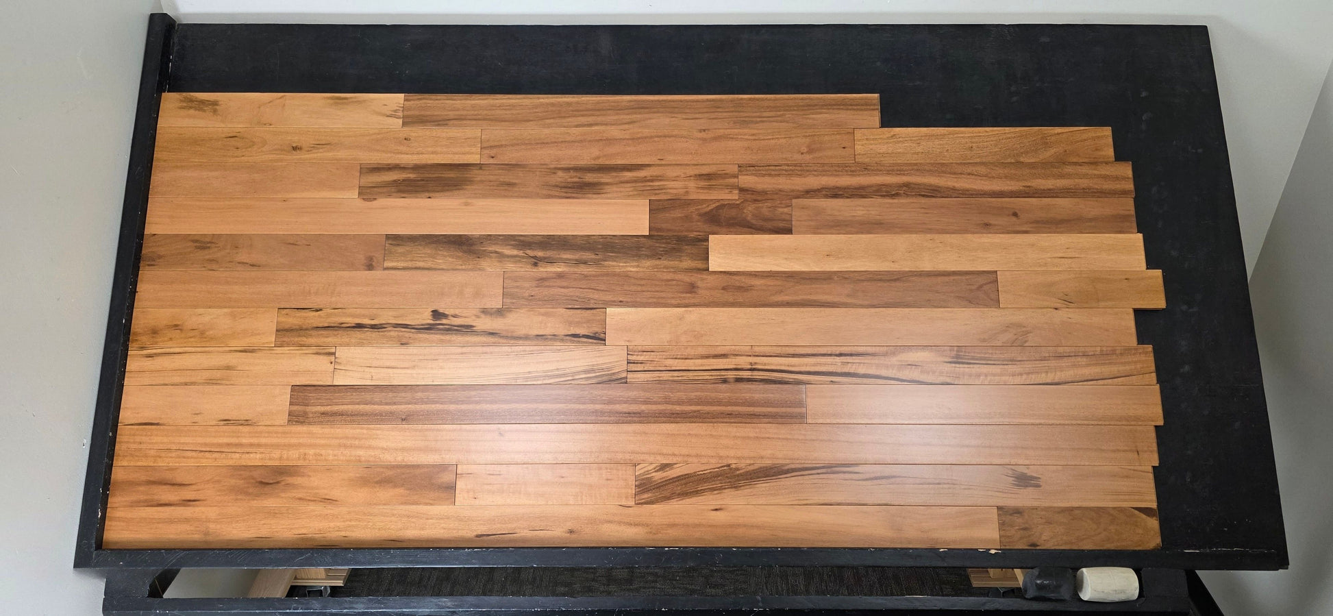 3 1/4" x 3/4" Solid Prefinished Tigerwood Hardwood Flooring. Shown on a black shooting table. Shot from center. 