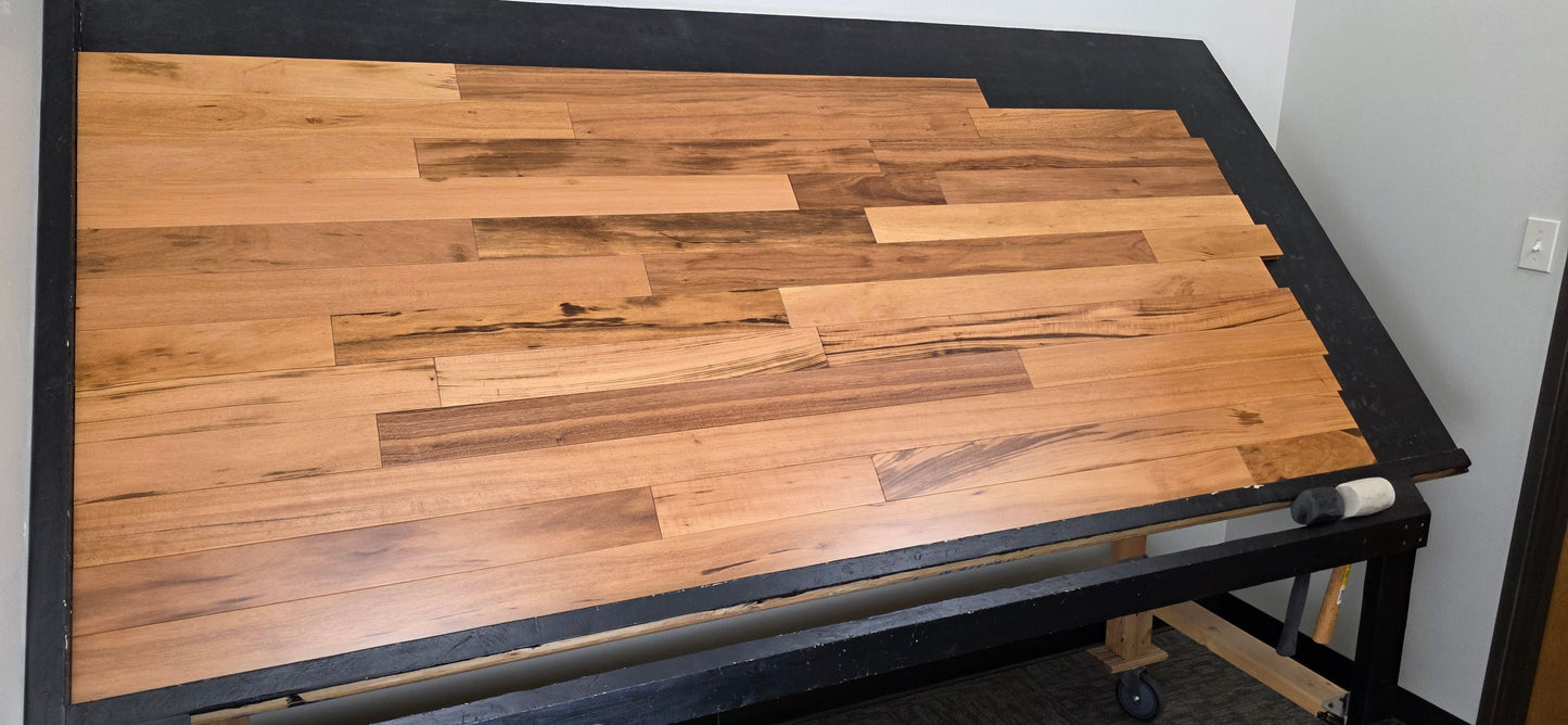 3 1/4" x 3/4" Solid Prefinished Tigerwood Hardwood Flooring. Shot from steep left. Shown on a black shooting table. 