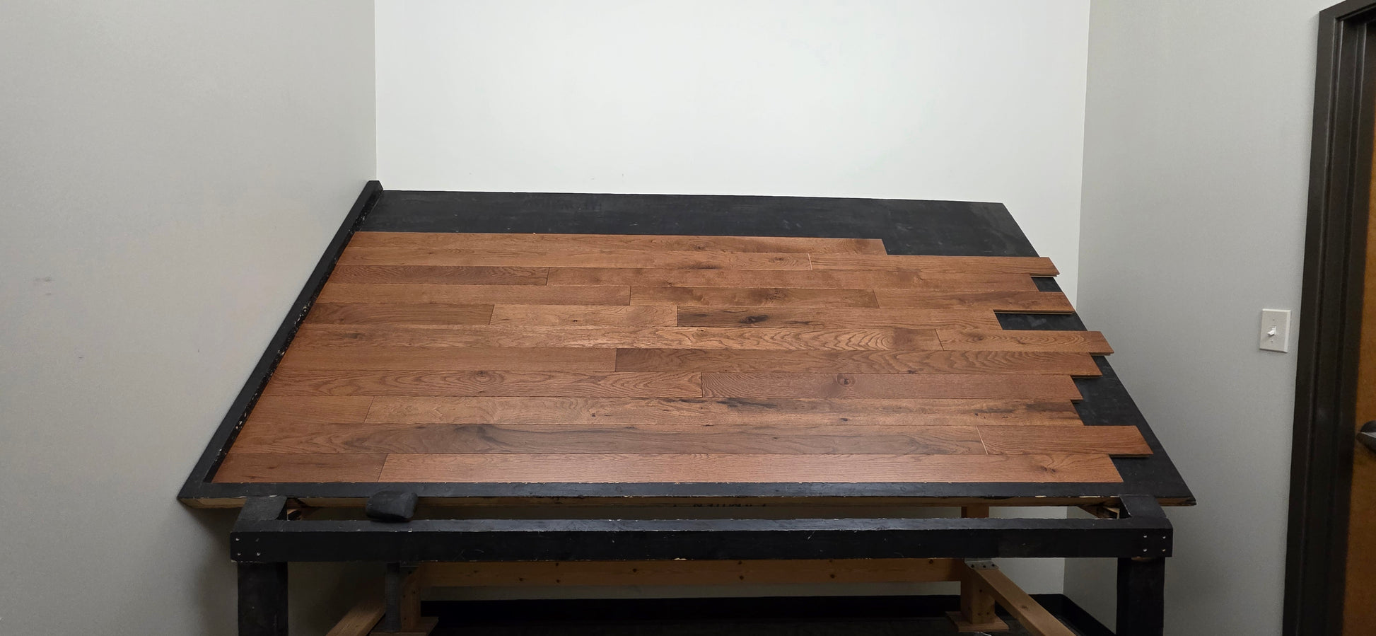 Table shot of Red Oak Gunstock Character Grade Hardwood Flooring on a black table 