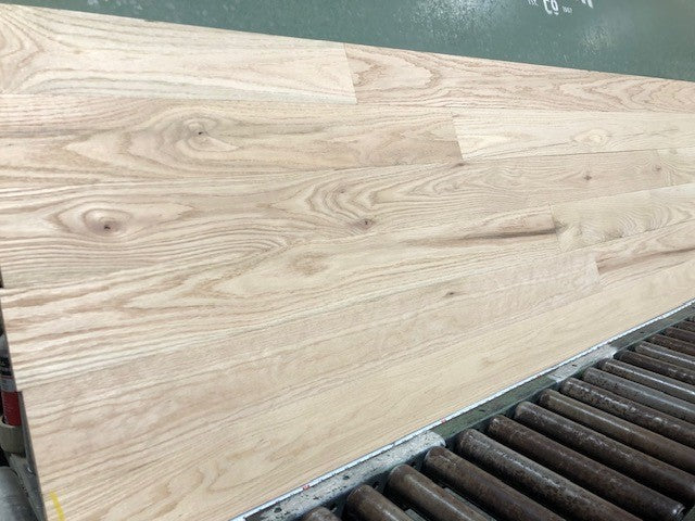 Unfinished Red Oak #1 Common Solid Hardwood Flooring. Shown on a green racking table. 