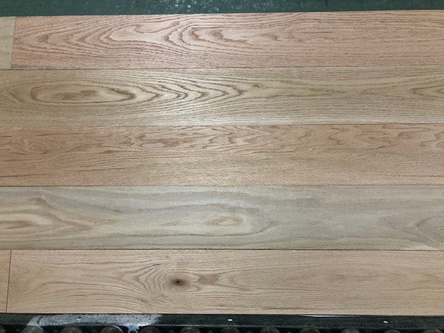 Unfinished Red Oak #1 Common Solid Hardwood Flooring. Shown on a green shooting rack.