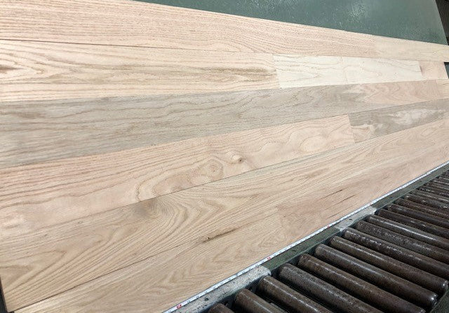 Unfinished Red Oak #1 Common Solid Hardwood Flooring. Show on a green racking table, steep left angle.