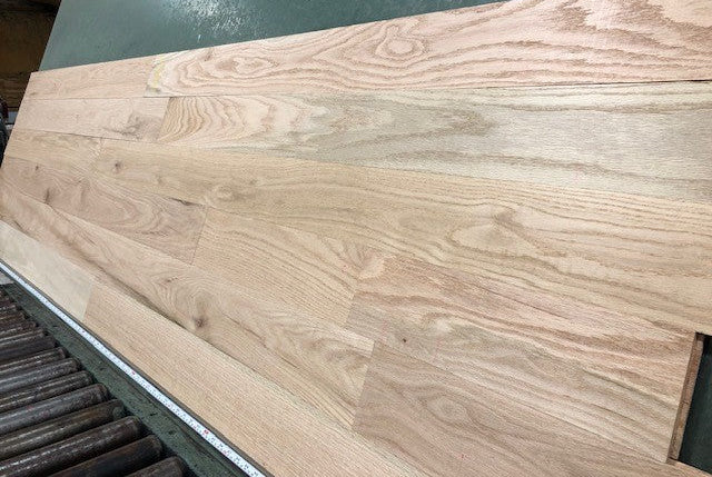 Unfinished Red Oak #1 Common Solid Hardwood Flooring. Wide right angle shot on a green racking table.