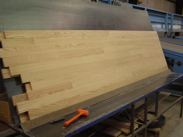  Unfinished Red Oak Select & Better Solid Hardwood Flooring on a black and blue racking machine with an orange mallet